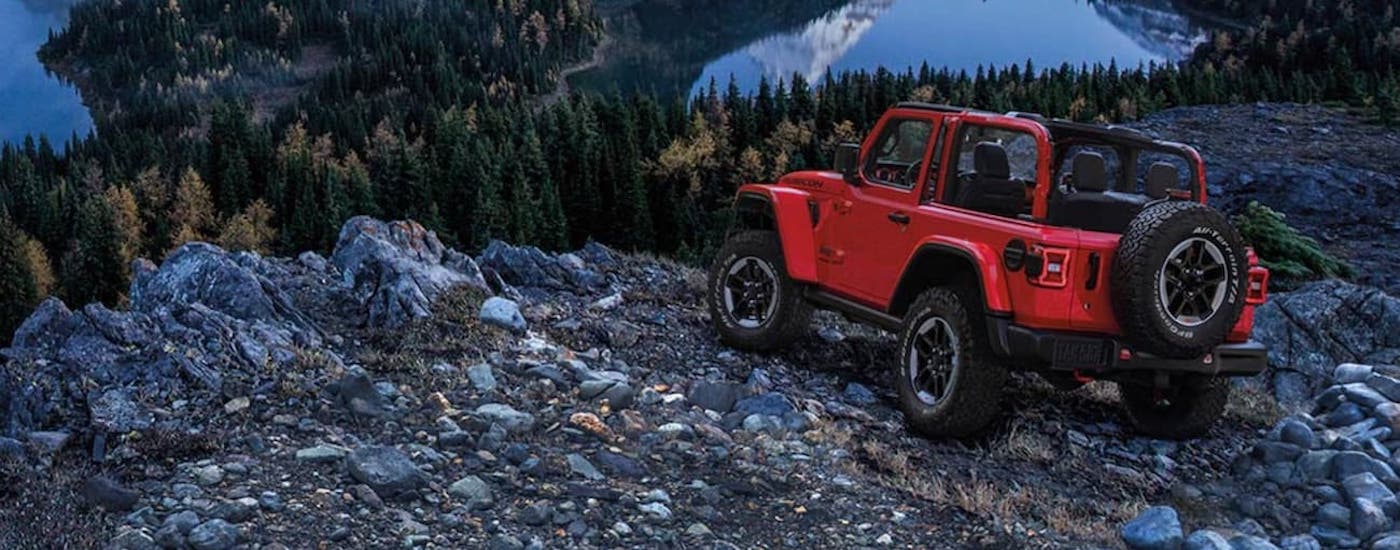 A red 2023 Jeep Wrangler is shown from the rear at an angle while off-road.