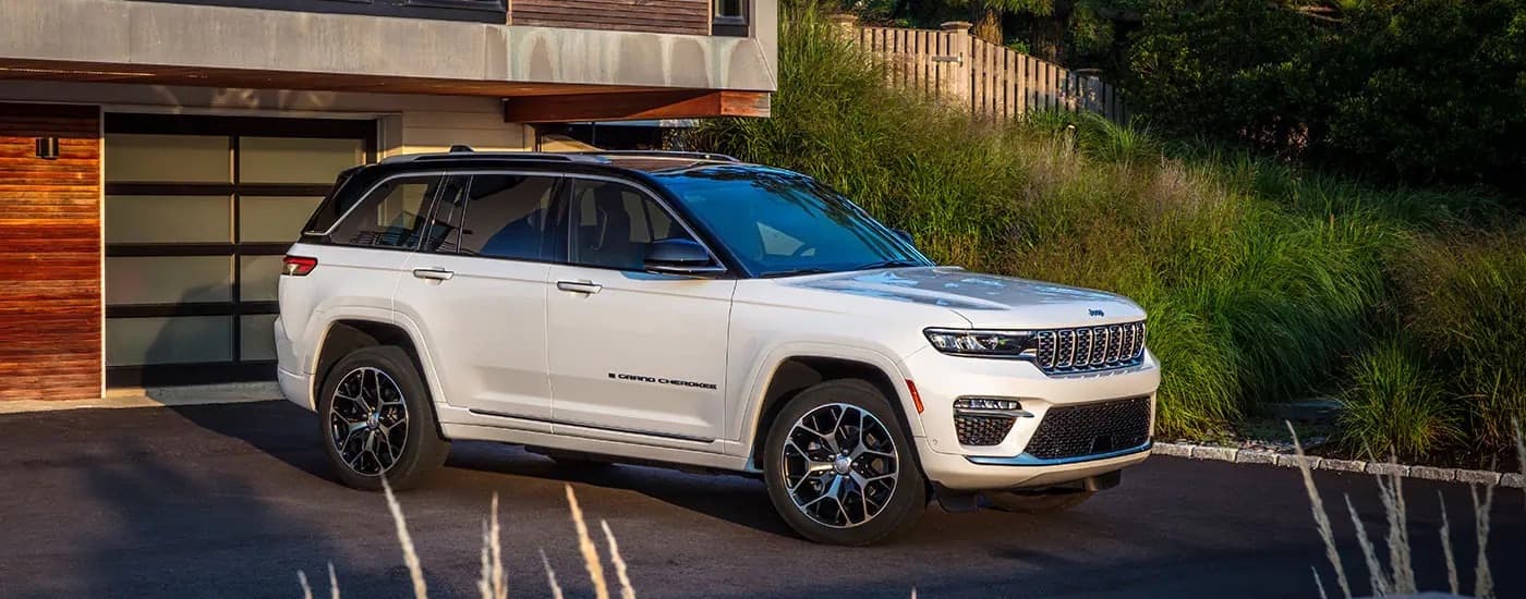 A white 2022 Jeep Grand Cherokee is shown from the side while parked on a driveway.