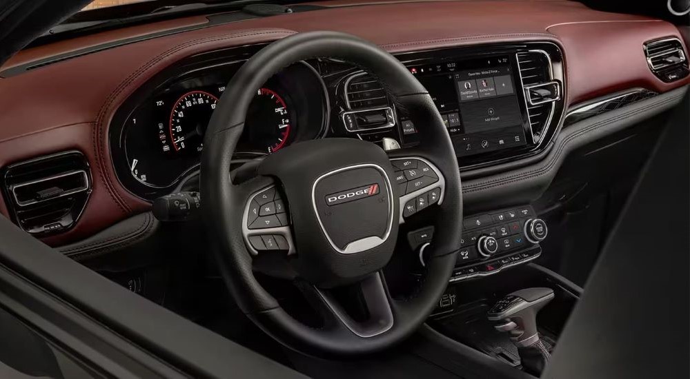 A close up shows the maroon and black interior and steering wheel in a 2024 Dodge Durango.