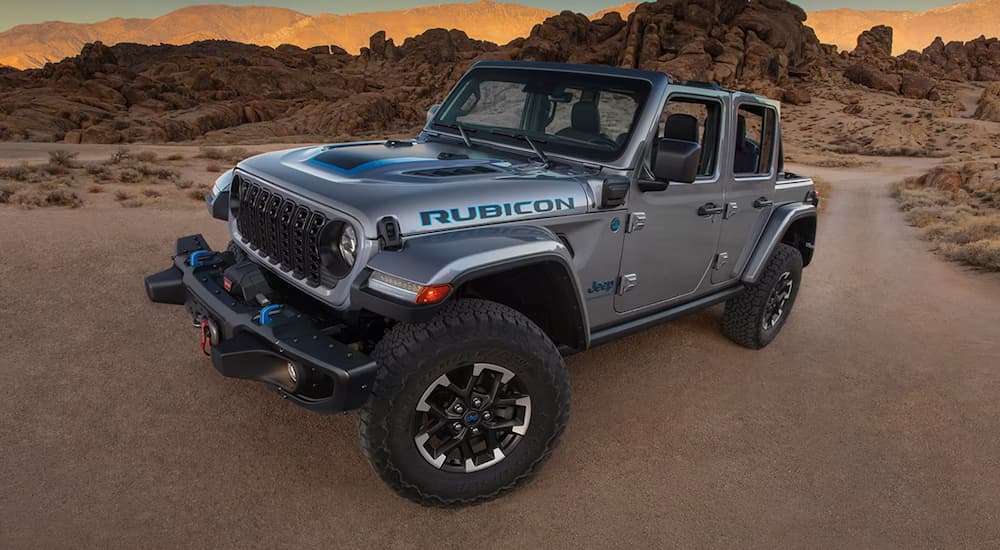 A silver 2024 Jeep Wrangler Rubicon 4xe parked in the desert at sunset.