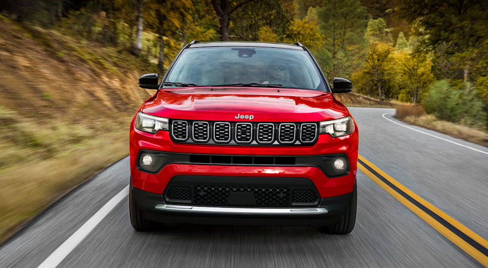 Head-on view of a red 2024 Jeep Compass driving to a Jeep dealer near Morton.