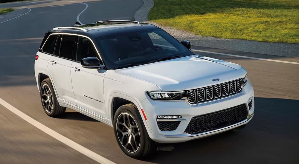 A white 2024 Jeep Grand Cherokee driving in the sun.