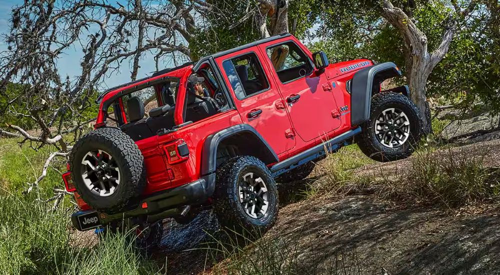 A red 2025 Jeep Wrangler Rubicon off-roading uphill.