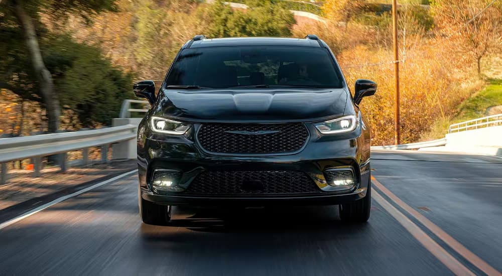 A black 2025 Chrysler Pacifica driving down a street