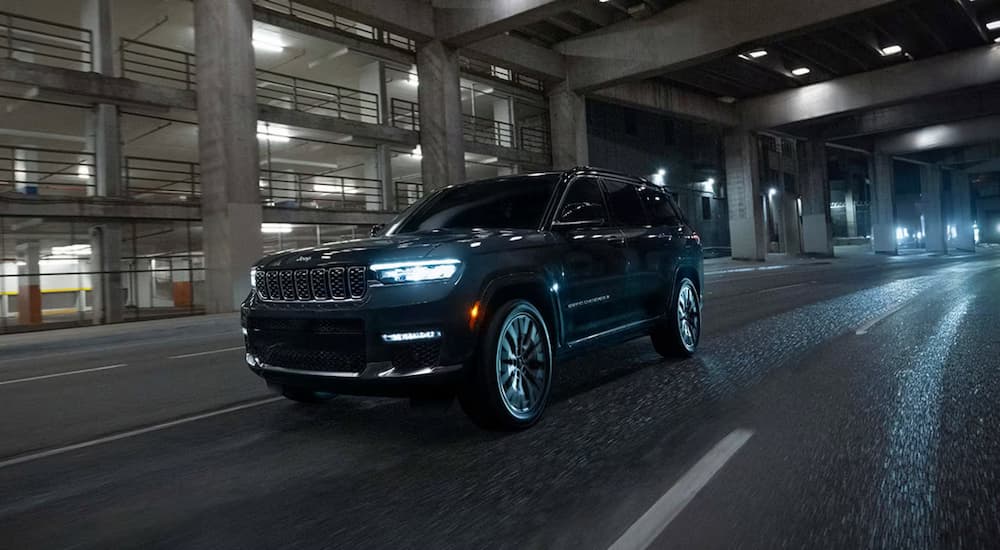 A black 2025 Jeep Grand Cherokee driving down a highway at night