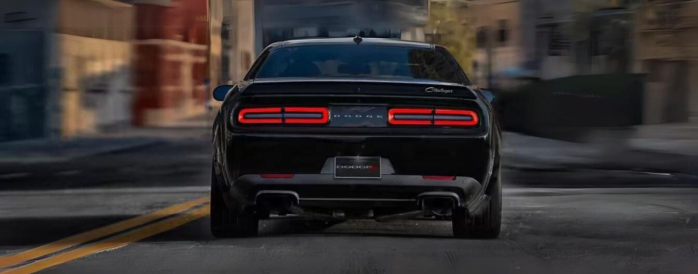 A black 2023 Dodge Challenger is shown from the rear after leaving a dealer that has used cars for sale.