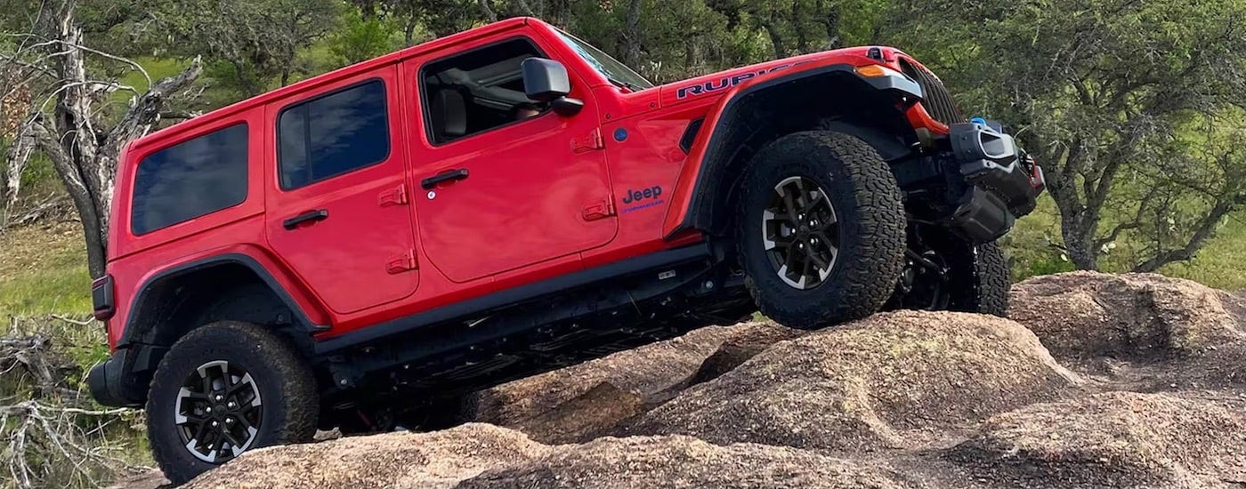 A red 2024 Jeep Wrangler Rubicon 4xe is shown from the side after leaving a Jeep dealer near Morton.