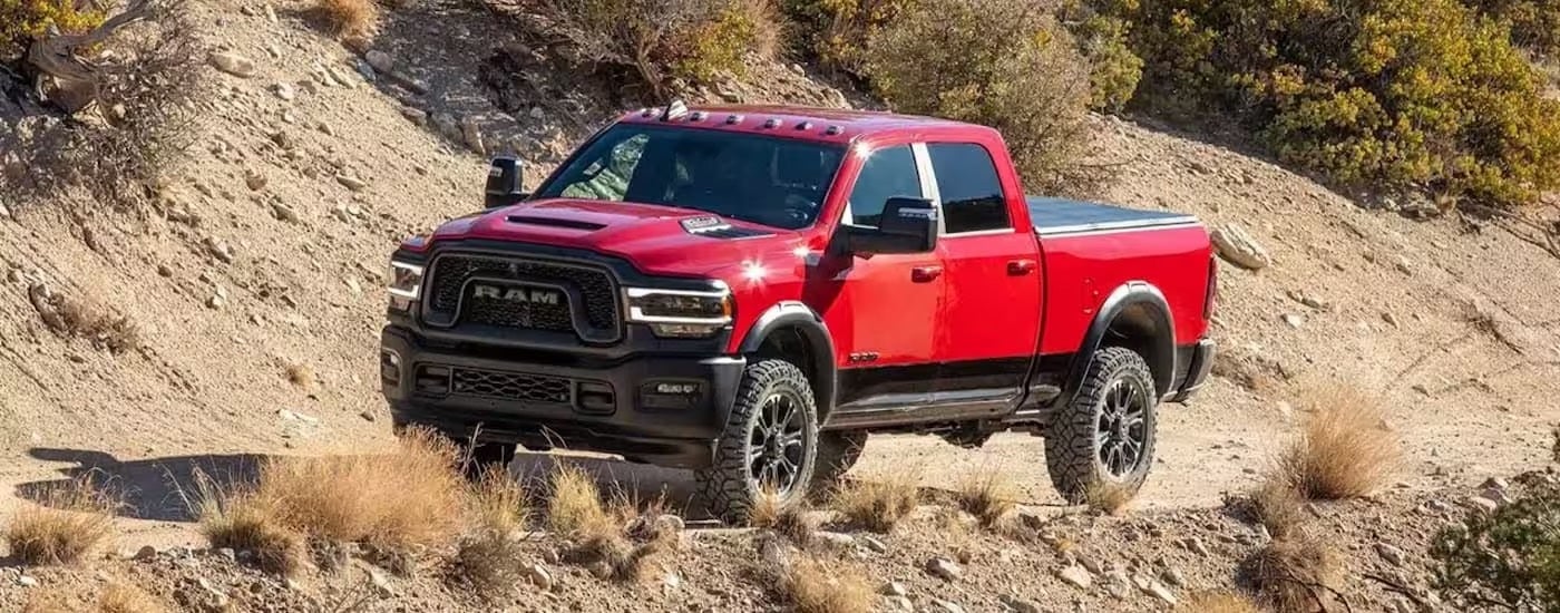 A red 2024 Ram 2500 off-roading on a rocky hill.
